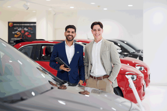 Zwei junge Herren stehend hinter einem Auto